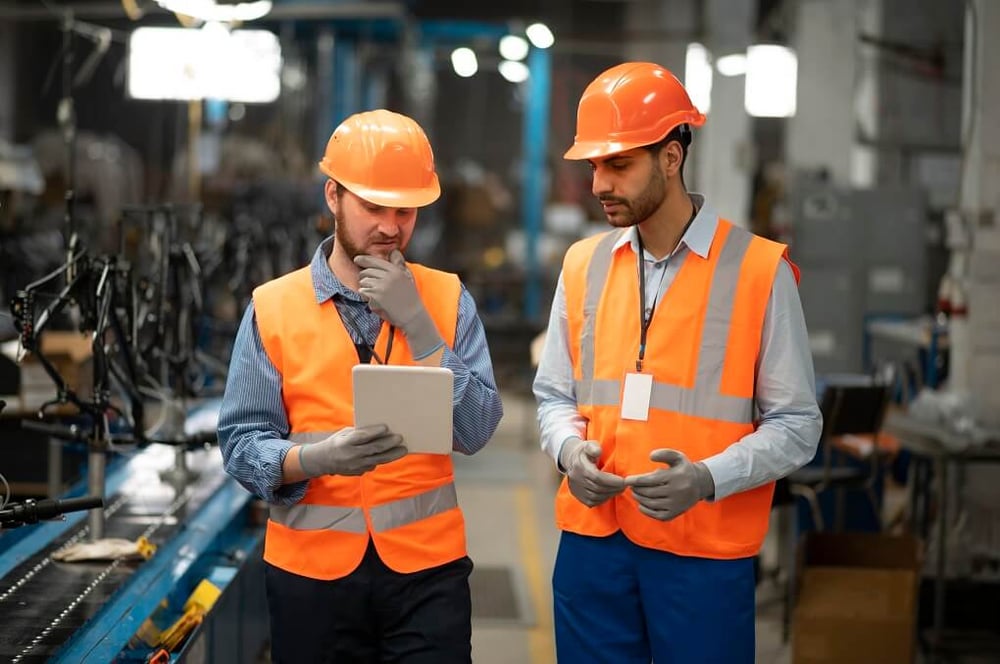 Deux ouvriers d'usine analysent une tablette